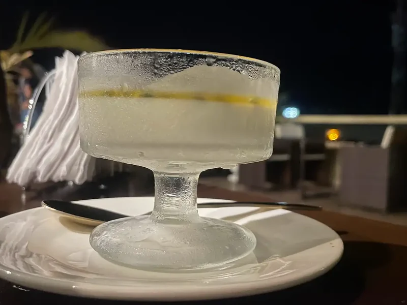 A pale chilled drink in a stemmed glass on a white saucer.